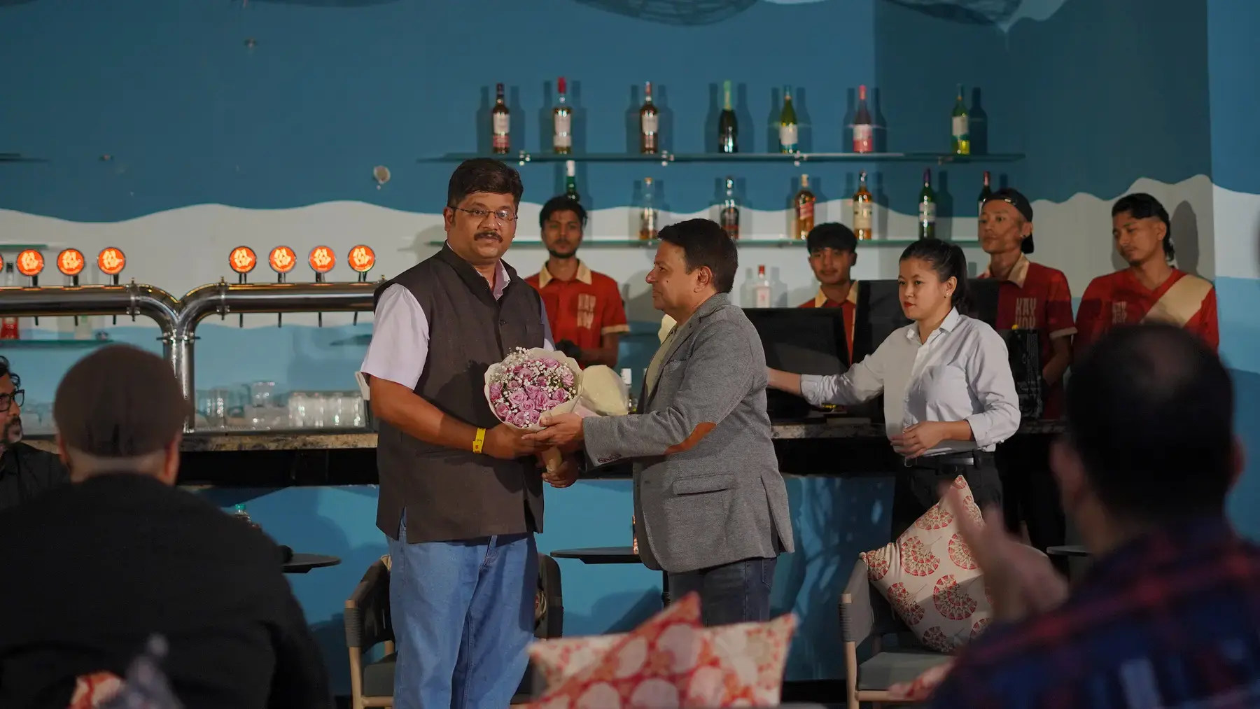 A bouquet being presented to a speaker beside the bar taps